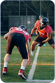 Two American football players in red and black uniforms facing each other on a field marked with white lines during a game or practice.